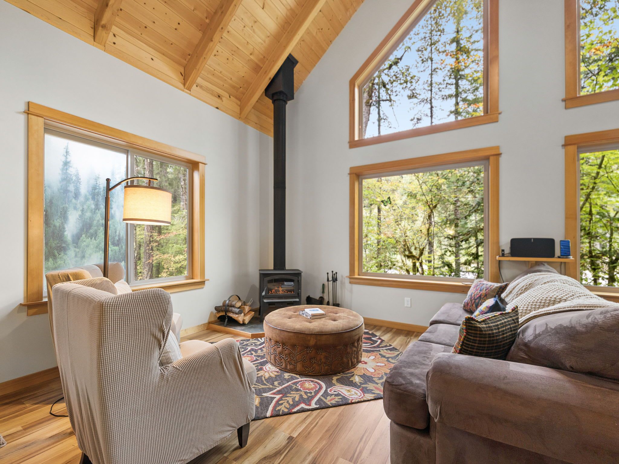A cozy living room with a fireplace, large windows, and a comfortable seating area.