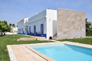 Un edificio moderno con piscina, zona de estar al aire libre y una pared de piedra.