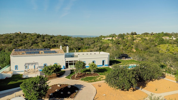A modern house with a solar panel roof, a swimming pool, and a well-maintained garden.
