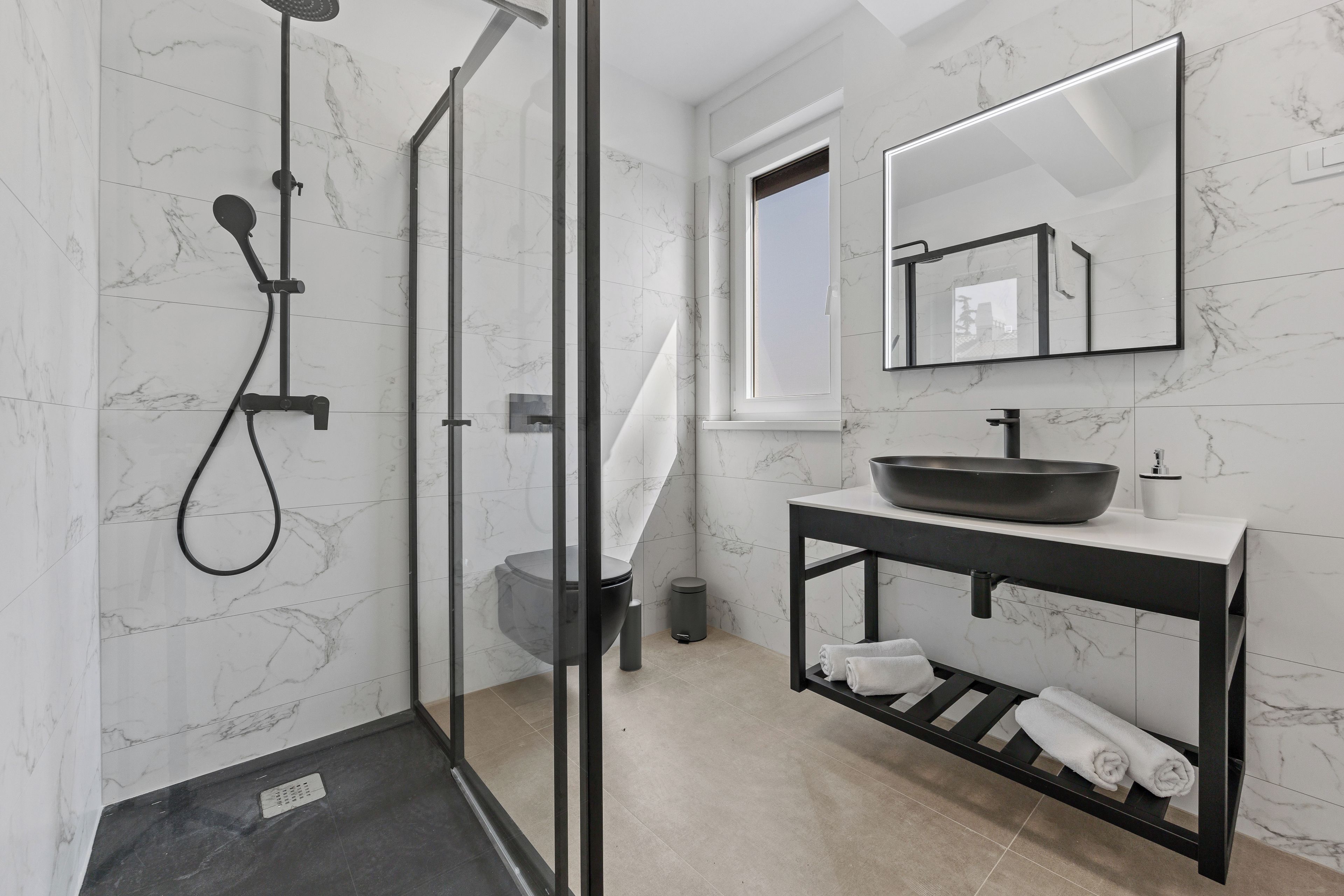 Une salle de bain moderne avec une douche à parois de verre, un lavabo avec un receveur et un miroir au-dessus du lavabo.