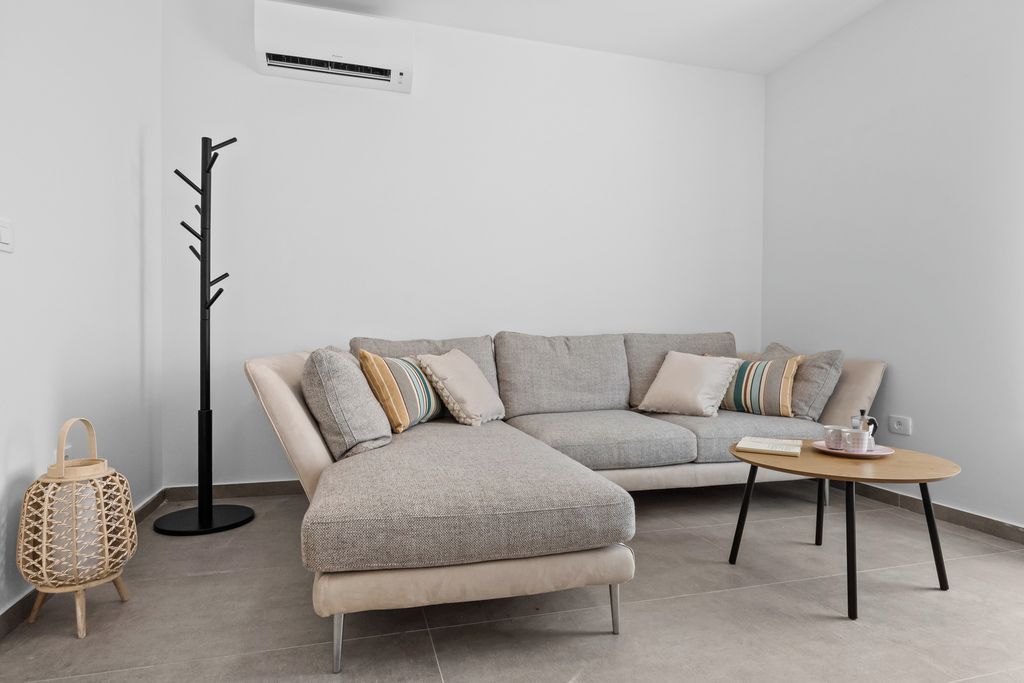 Una sala de estar moderna con un sofá seccional, una mesa de centro, una lámpara de pie y un farol decorativo.