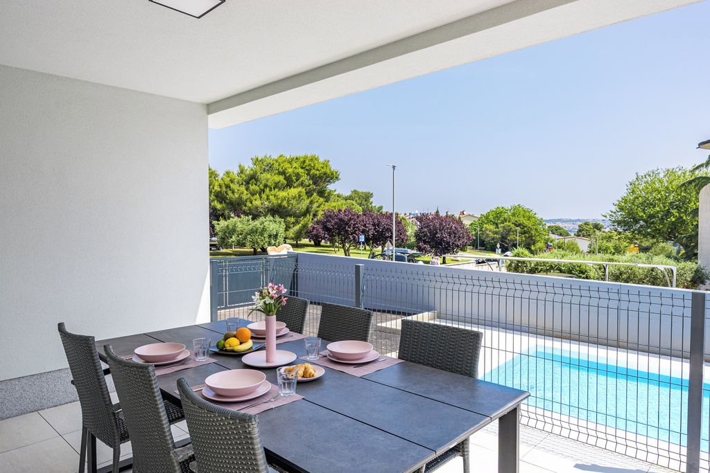 Un área de comedor al aire libre con una mesa para dos, con vista a una piscina.