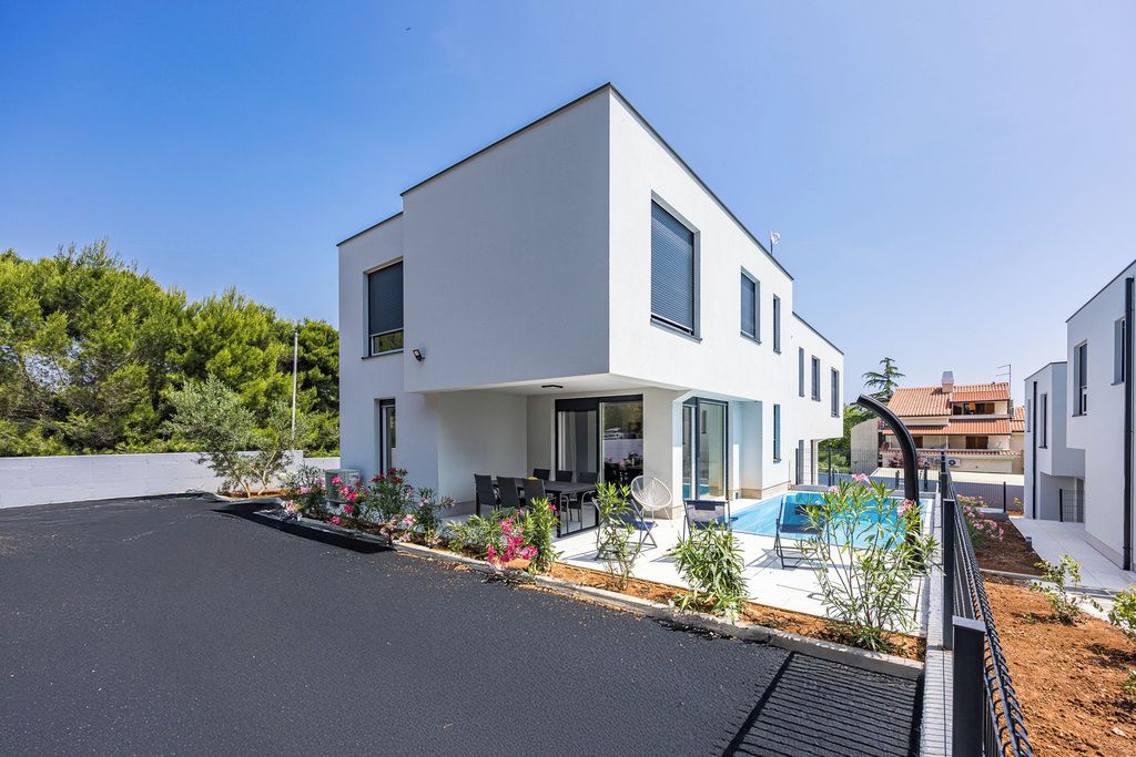 A modern two-story house with a swimming pool, outdoor seating, and a well-maintained garden.