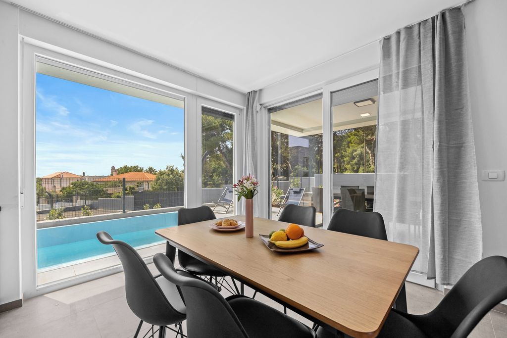 A dining area with a table, chairs, and a view of a swimming pool.
