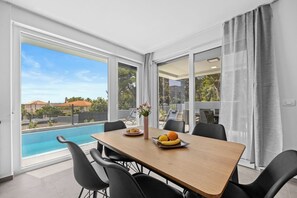 A dining area with a table, chairs, and a view of a swimming pool.