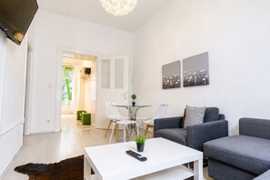 A modern living room with a white coffee table, grey sofas, and a dining area with white chairs. - Belvedere on Foot Your Vienna 1BR (Vienna)