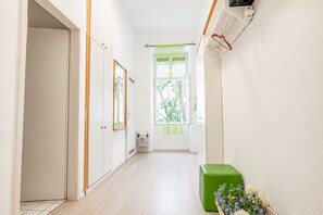 A hallway with a door on the left, a window with a curtain, and a green box with flowers on the right. - Belvedere on Foot Your Vienna 1BR (Vienna)