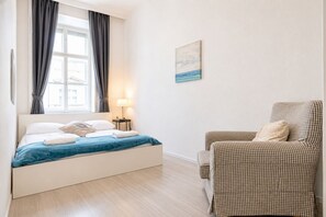 A bedroom with a bed, a chair, a lamp, and a painting on the wall. - Belvedere on Foot Your Vienna 1BR (Vienna)