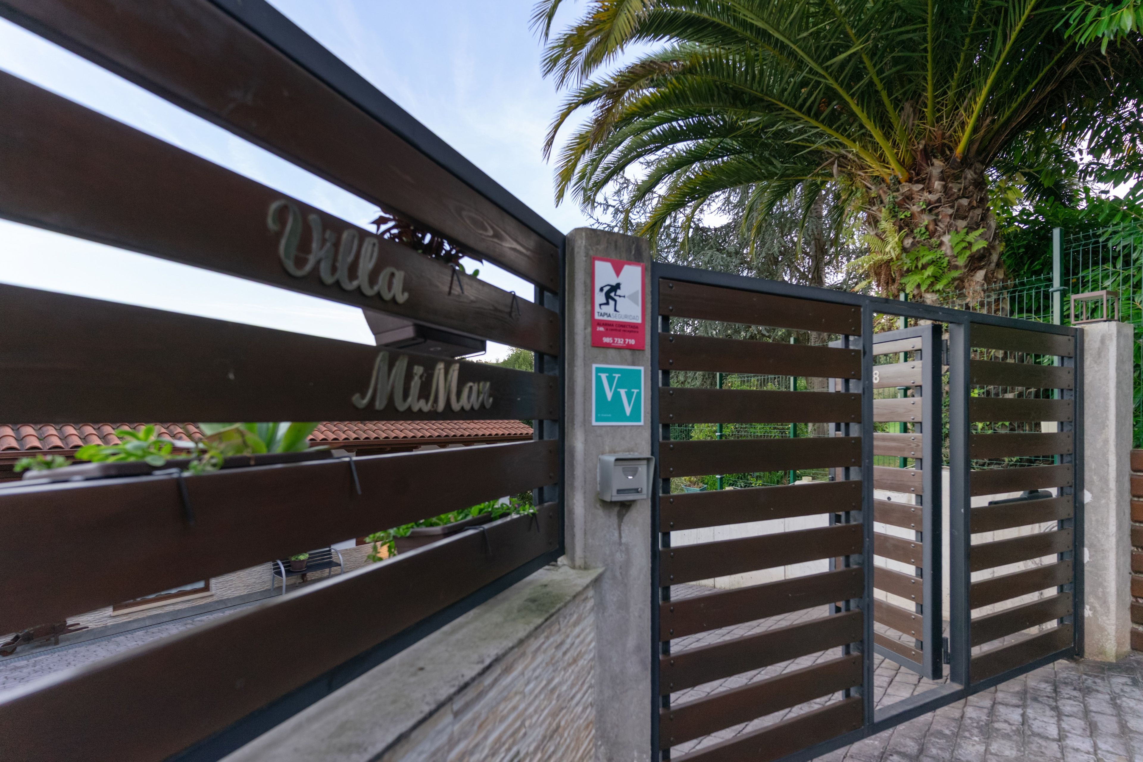 Una entrada cerrada con un cartel que dice 'Villa McNair' y un letrero de advertencia de seguridad.