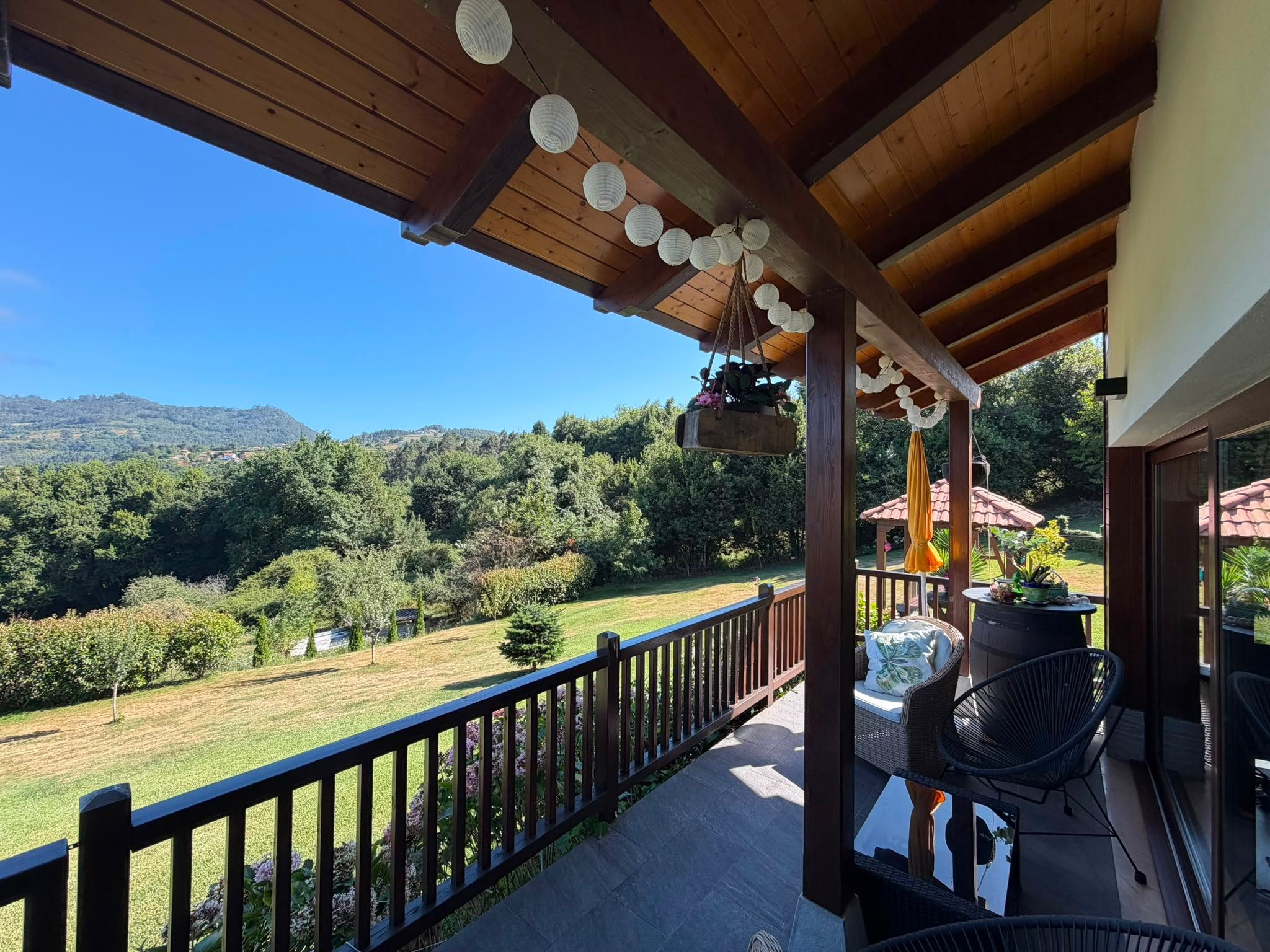 A wooden deck with a view of a green landscape and hills.