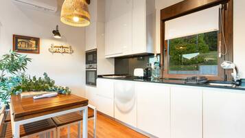 Una cocina moderna con armarios blancos, una mesa de comedor de madera y una lámpara colgante.