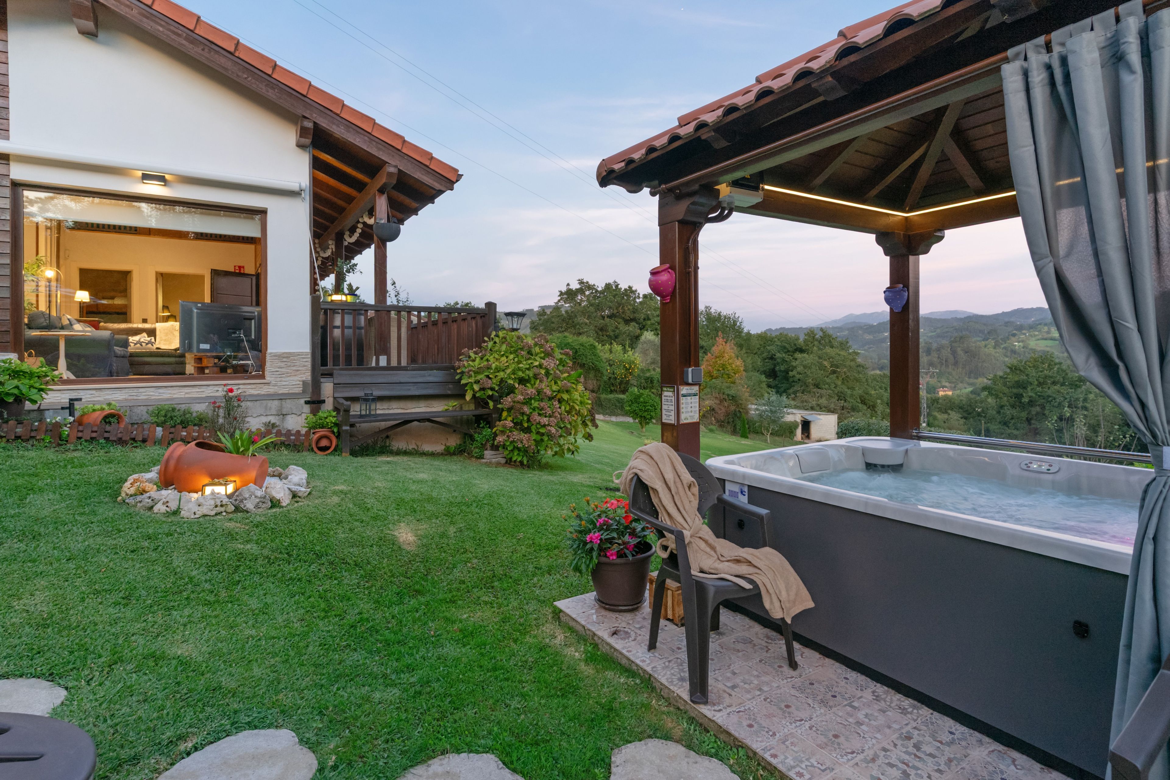 A patio area with a hot tub, a covered seating area, and a view of the surrounding landscape.