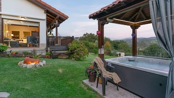 A patio area with a hot tub, a covered seating area, and a view of the surrounding landscape.