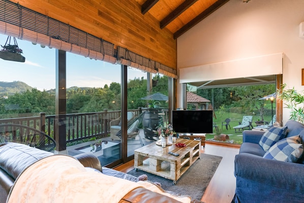 Una sala de estar moderna con un televisor grande, asientos cómodos y vistas a un jardín exuberante.