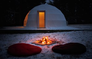 Paisaje nevado con una estructura en forma de cúpula blanca y una entrada iluminada.