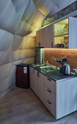 A compact kitchen with a stone backsplash, wooden cabinets, and a small sink.
