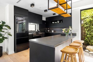 A modern kitchen with a central island, dark cabinetry, and a wooden ceiling structure. - Peaceful & Cozy 2 Bedroom House, Stunning Views (Los Angeles)