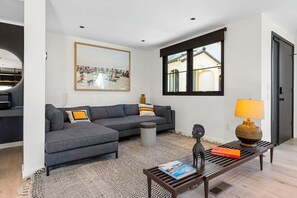 En moderne stue med en grå sofa, et sofabord, en lampe og et billede i ramme på væggen.