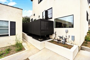 Un bâtiment moderne doté d’un toit plat, d’une structure verticale noire et d’une fenêtre avec un volet noir.