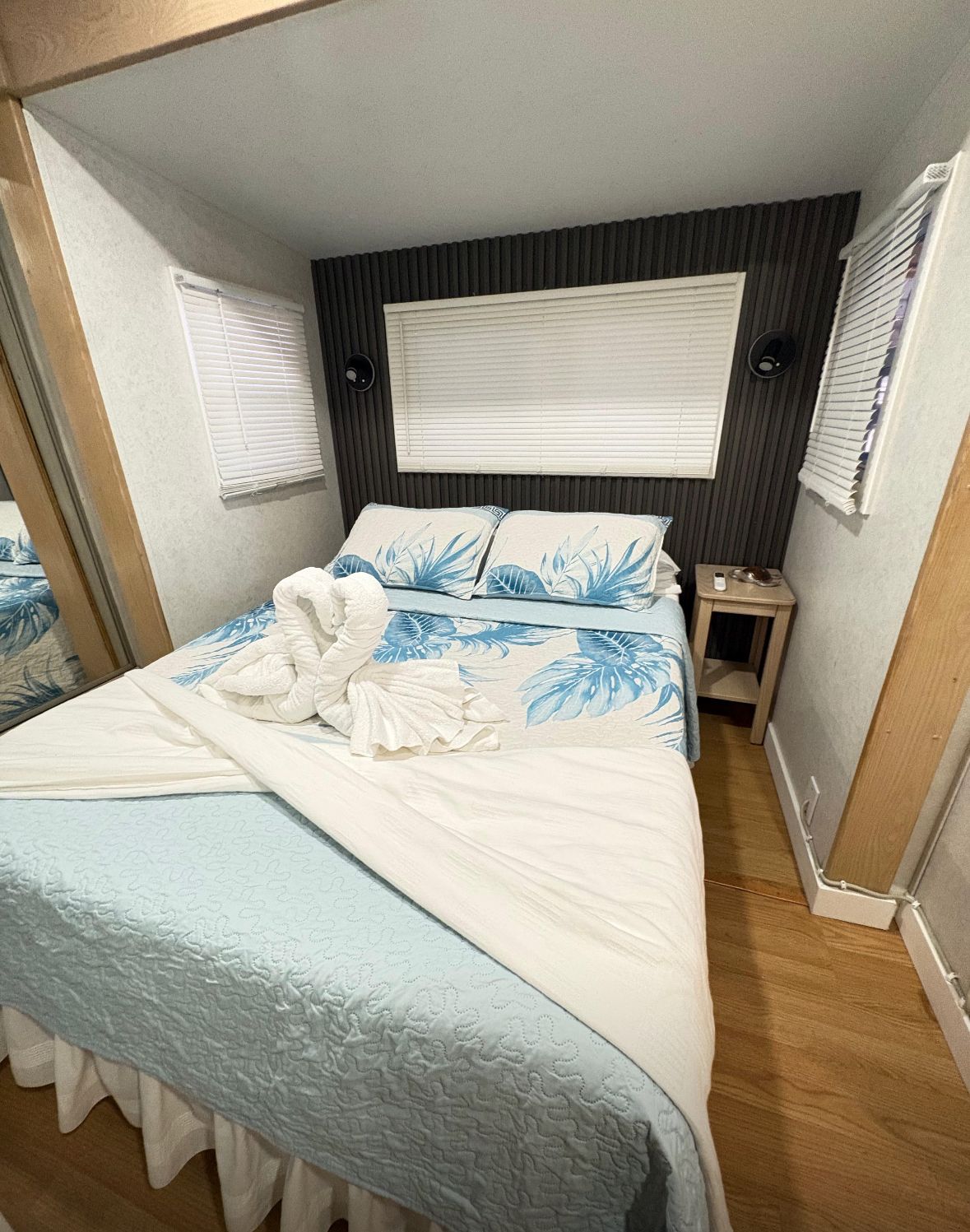 A compact bedroom with a bed, a bedside table, and a window with blinds.