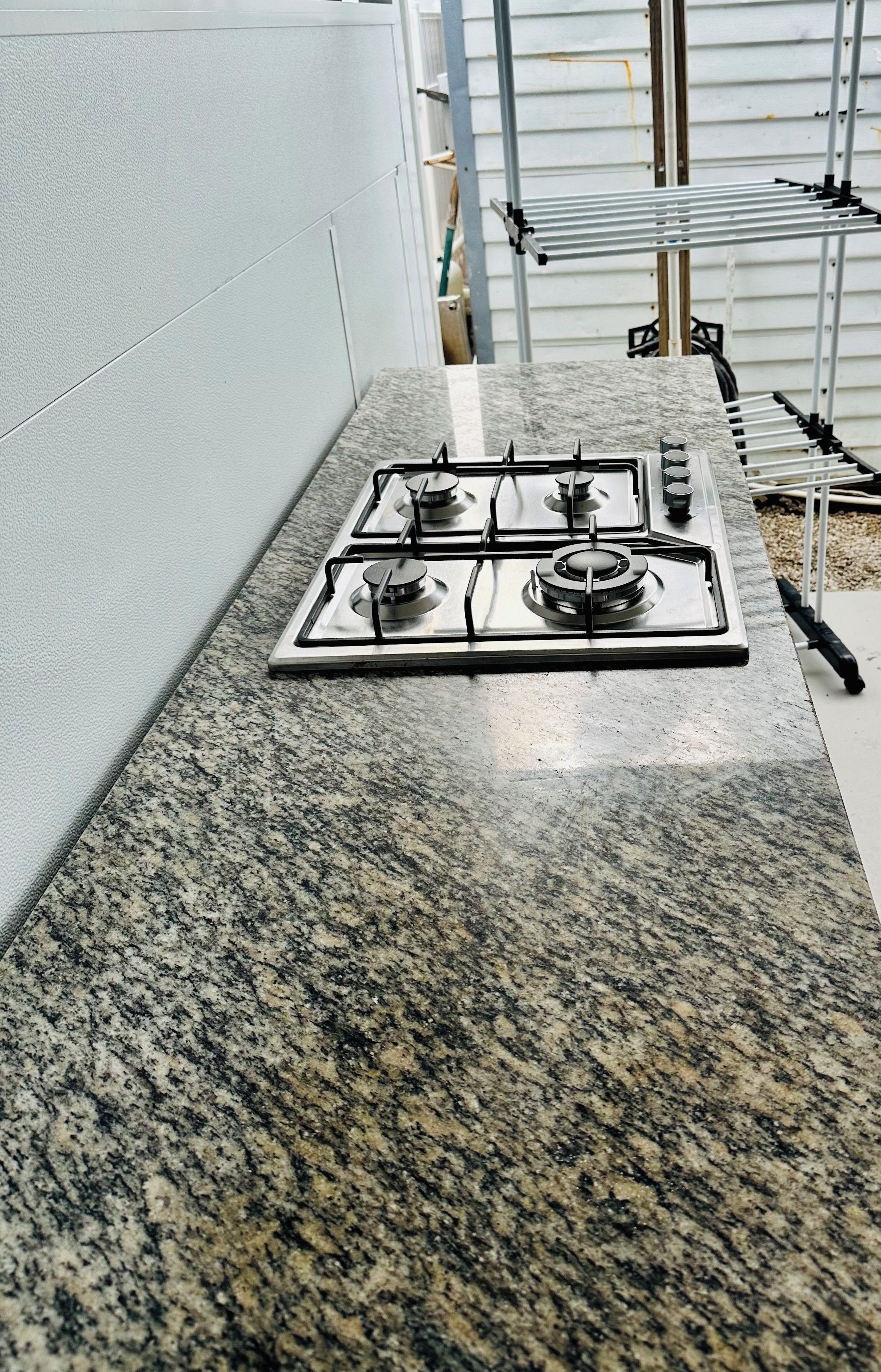 Cozinha com bancada de granito e fogão a gás.