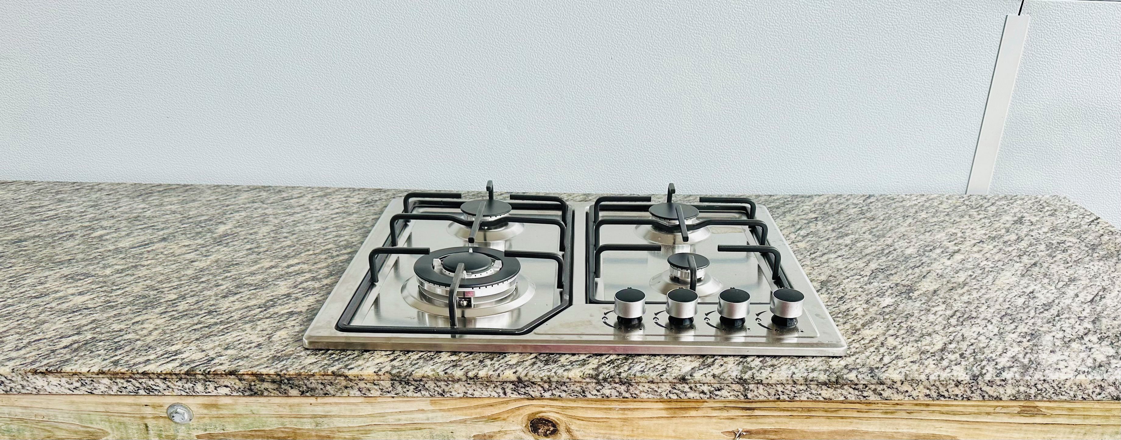 A gas stove with four burners and a control knob on a granite countertop.