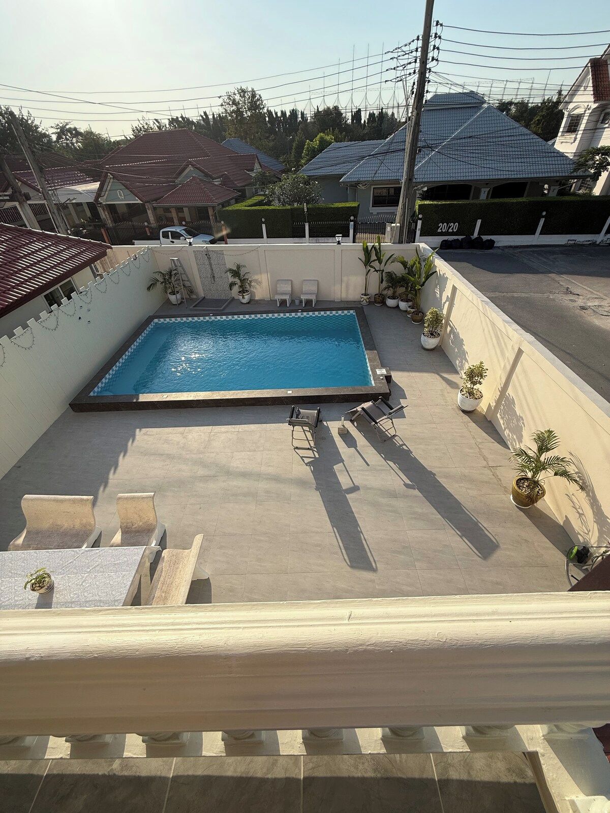 A rooftop swimming pool with lounge chairs and potted plants.