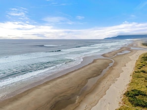A coastal beach with waves, a sandy shore, and distant land.