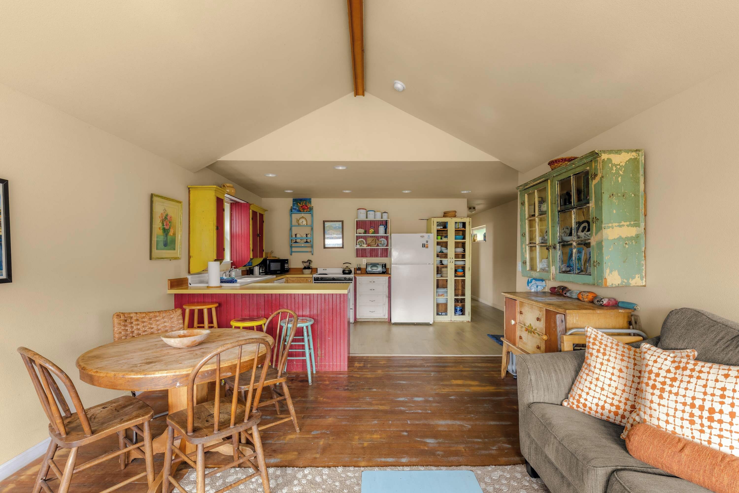 Eine gemütliche Küche mit Holzmöbeln, ein Essbereich mit Tisch und Stühlen sowie ein Wohnzimmer mit Sofa und Kissen.