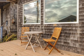 A wooden deck with two wooden chairs and a small round table.