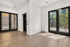 A modern interior with a wooden floor, a black door, and a view of the outdoors. - Chic 1BR Downtown Fort Worth ; Sleeps 4 ; Near Sundance & Dickies (Fort Worth)