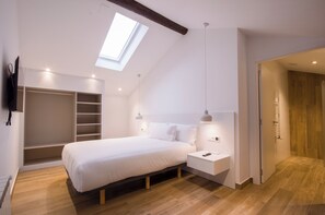A bedroom with a skylight, a bed, bedside tables, a wardrobe, and a walk-in closet. - TWO-BEDROOM APARTMENT (castroverde)