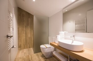 A modern bathroom with a wooden floor, a white sink, and a toilet. - TWO-BEDROOM APARTMENT (castroverde)