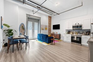 A modern living room with a dining area, kitchen, and a brick accent wall. - Lux Executive Suite: Sleeps 4; Heart of Columbus (Columbus)