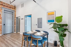 A dining area with a table set for four, a large plant, and a modern art piece on the wall. - Lux Executive Suite: Sleeps 4; Heart of Columbus (Columbus)