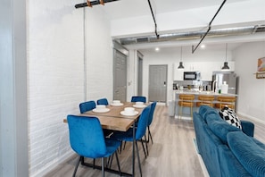 Een moderne keuken met roestvrijstalen apparatuur, een eethoek met blauwe stoelen en een blauwe bank.