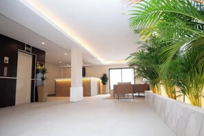 A spacious lobby with a reception desk, seating area, and a large potted plant. - Chabella! Charm Beach Lofts & Apartments WITH OCEAN VIEWS (Carvoeiro)
