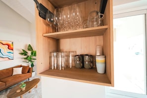 A wooden shelf with various glassware and mugs. - Casa Sinku Solo - Bohemian Bungalow Curacao (Willemstad)