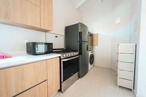 A compact kitchen with a microwave, stove, oven, and refrigerator. - Casa Sinku Solo - Bohemian Bungalow Curacao (Willemstad)