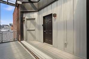 A building with a metal exterior, a wooden deck, and two doors; one labeled 'EXIT' and the other marked '3G'. - Luxury Studio Living: Sleeps 2; Heart of Columbus (Columbus)