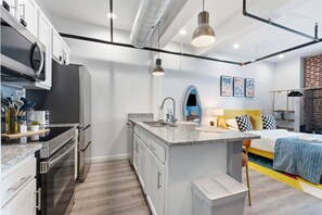 A modern kitchen with stainless steel appliances, a granite countertop, and a small island with a sink. - Luxury Studio Living: Sleeps 2; Heart of Columbus (Columbus)
