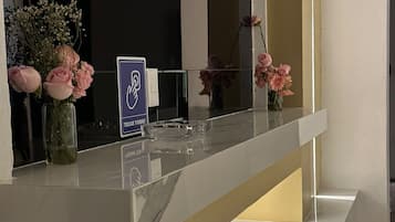 Un mostrador de recepción con encimera de mármol, un letrero que indica un spa y varios floreros con flores.