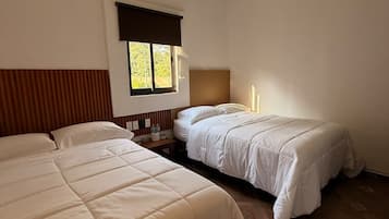 A room with two beds, a ceiling fan, a window with blinds, and a wall-mounted light fixture.