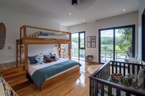A bedroom with a bunk bed, a large window with a view, and a balcony with a railing. - Seasons at Ceiba | Staffed Luxury House + Gym (Pinilla)