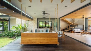 A modern bedroom with a wooden bed, a staircase, and a view of the outdoors. - Seasons at Ceiba | Staffed Luxury House + Gym (Pinilla)