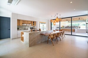 Une cuisine moderne avec un îlot central, des chaises en bois et des luminaires suspendus.