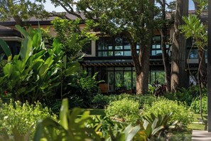 A modern building with large windows and a garden with various plants. - Seasons at Ceiba | Staffed Luxury House + Gym (Pinilla)