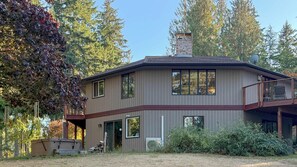 A two-story house with a balcony, a chimney, and a garage. - Modern 3BR Retreat with Sauna & Hot Tub Sleeps 8 (Sequim)