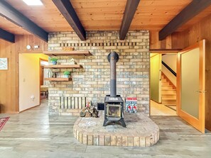 Ein Zimmer mit Kamin, Holzbalken, einer Ziegelwand und einer Treppe.