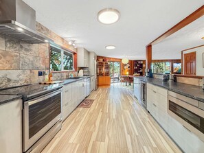 Una cuina moderna amb una illa central, electrodomèstics integrats i vista cap a l'exterior.